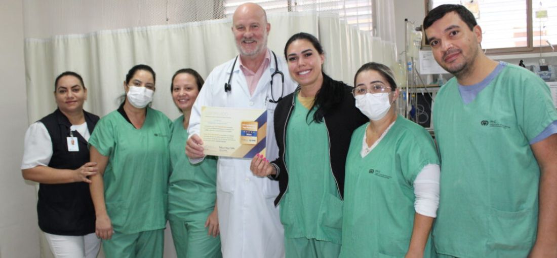 O diretor médico do IMC, cardiologista Luciano Miola, segura a certificação "UTI Top Performer", ladeado por profissionais da unidade
